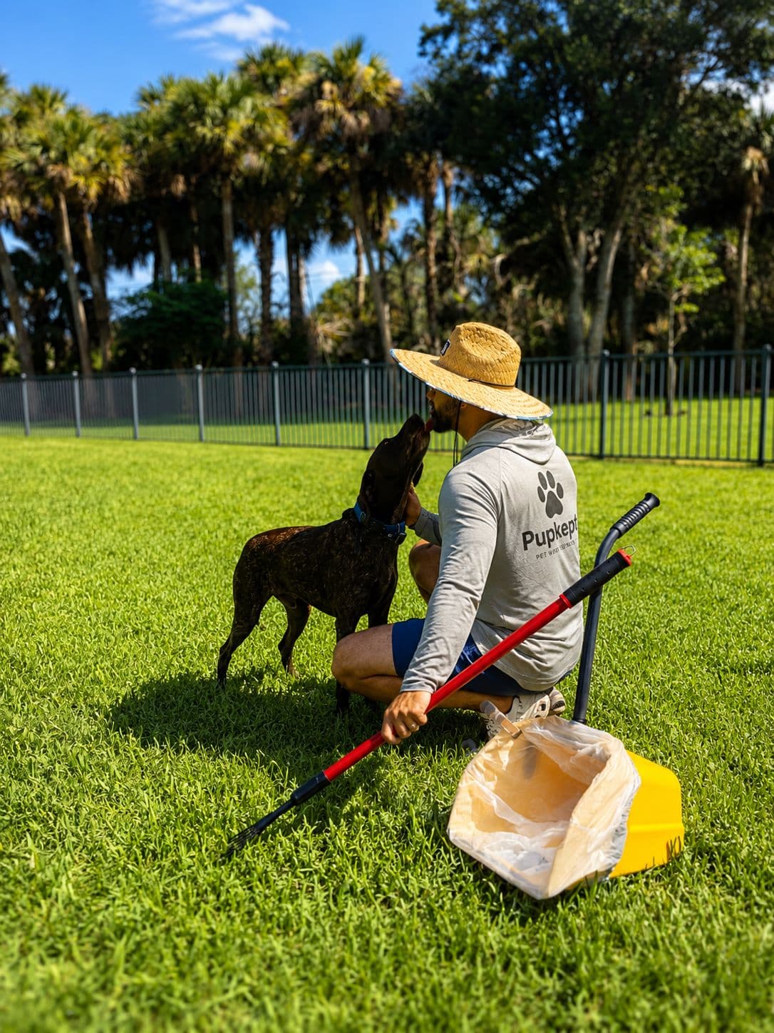 Pupkept technician with poop-scooping tools and a happy dog in a freshly cleaned Vero Beach backyard
